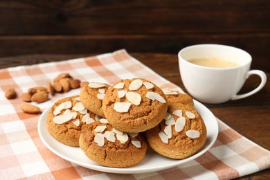 Photo of Tasty cookies with almond flakes and coffee on wooden table, closeup