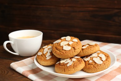 Photo of Tasty cookies with almond flakes and coffee on wooden table, closeup