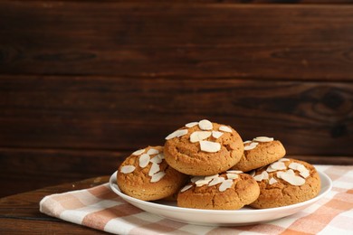 Photo of Tasty cookies with almond flakes on wooden table. Space for text