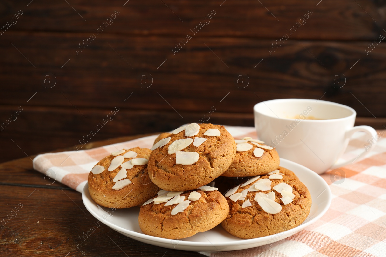 Photo of Tasty cookies with almond flakes and coffee on wooden table, closeup