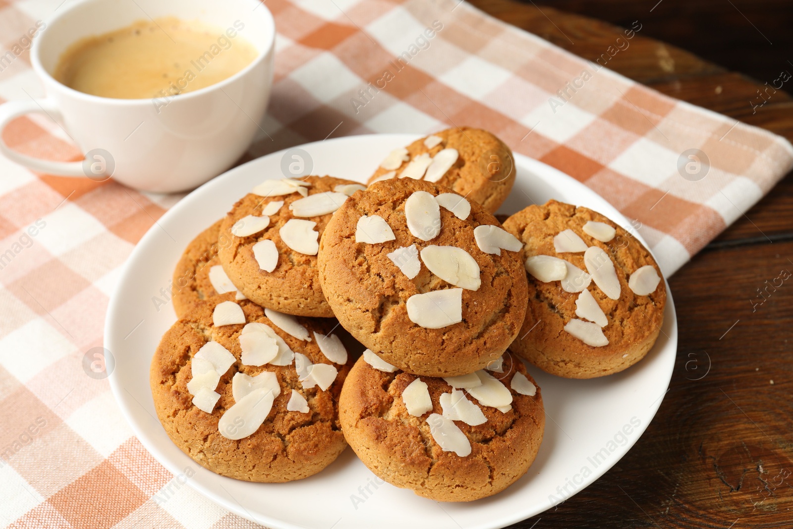 Photo of Tasty cookies with almond flakes and coffee on wooden table, closeup