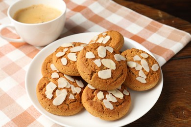 Photo of Tasty cookies with almond flakes and coffee on wooden table, closeup