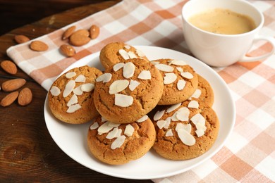 Photo of Tasty cookies with almond flakes, nuts and coffee on wooden table, closeup