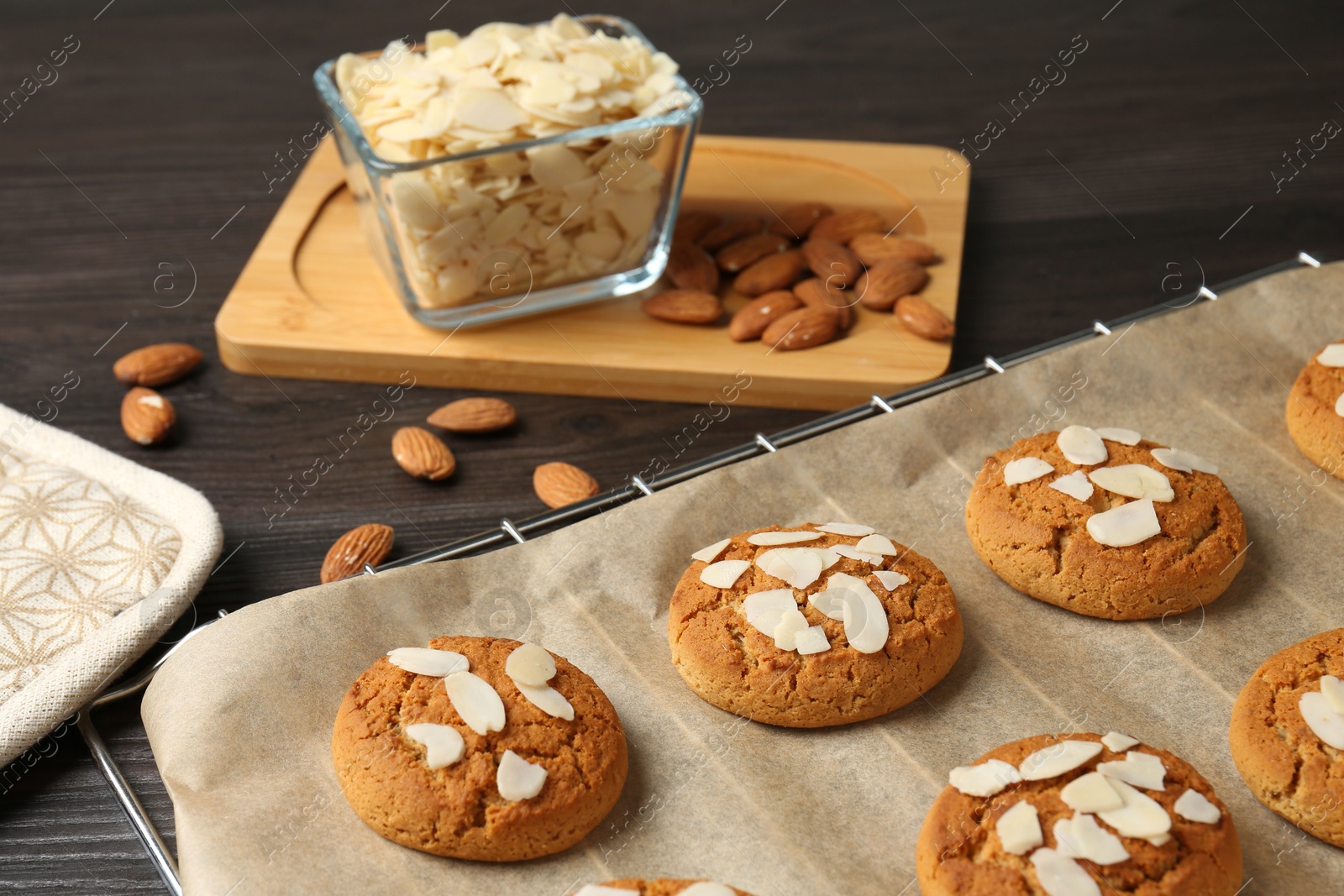 Photo of Tasty cookies with almond flakes and nuts on wooden table, closeup