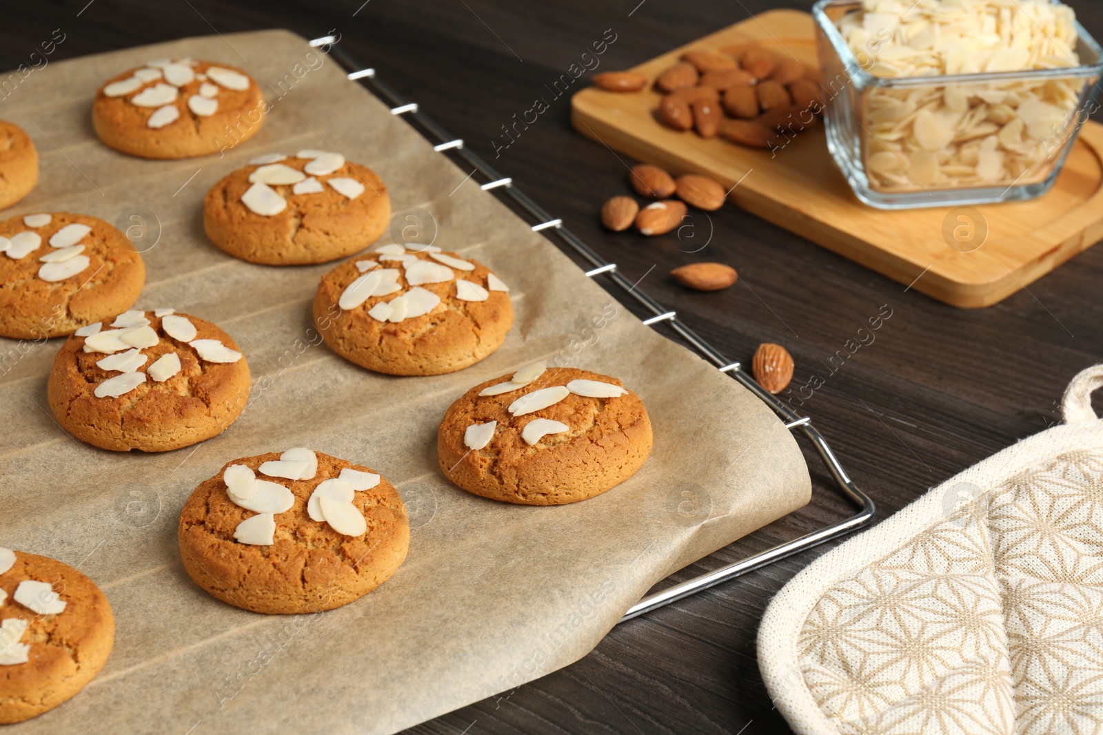 Photo of Tasty cookies with almond flakes and nuts on wooden table, closeup