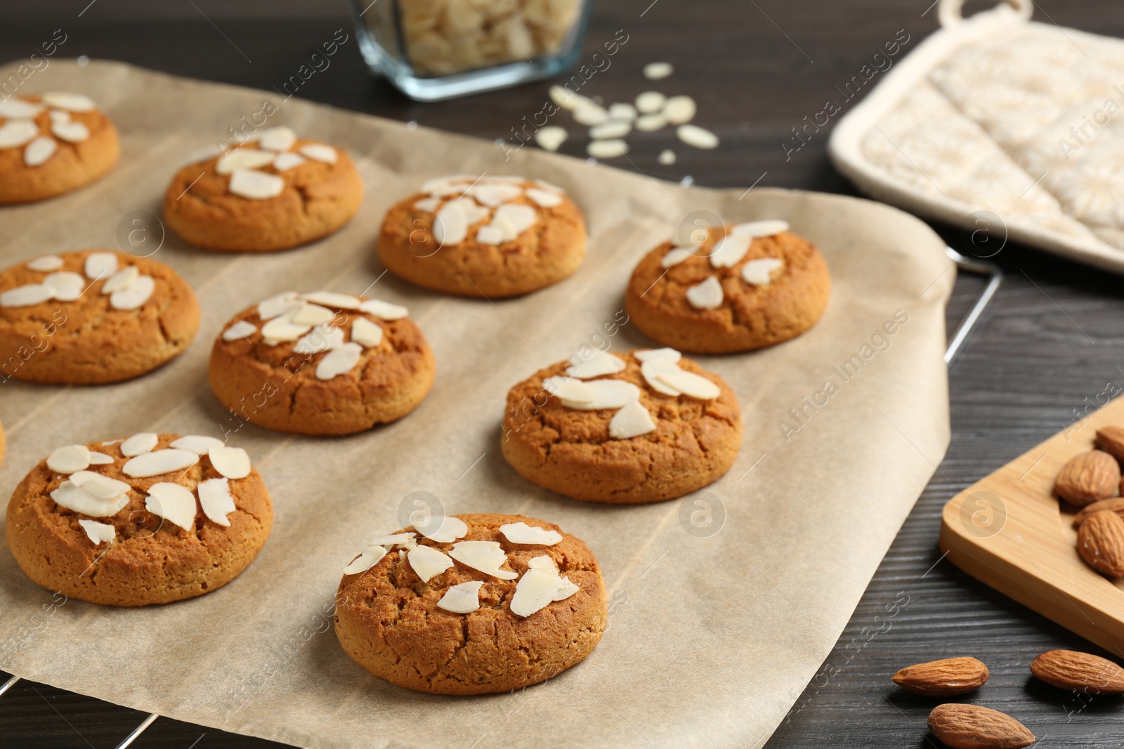 Photo of Tasty cookies with almond flakes and nuts on wooden table, closeup