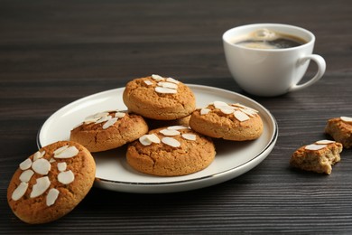 Photo of Tasty cookies with almond flakes and coffee on wooden table, closeup