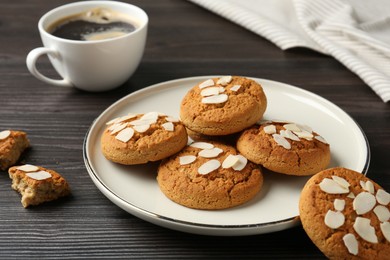 Photo of Tasty cookies with almond flakes and coffee on wooden table, closeup