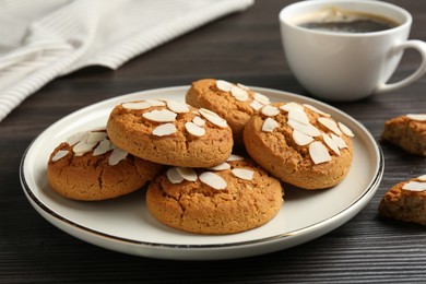 Photo of Tasty cookies with almond flakes and coffee on wooden table, closeup