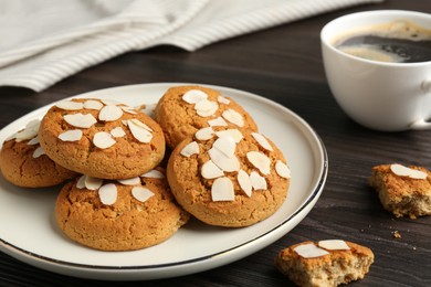 Photo of Tasty cookies with almond flakes and coffee on wooden table, closeup