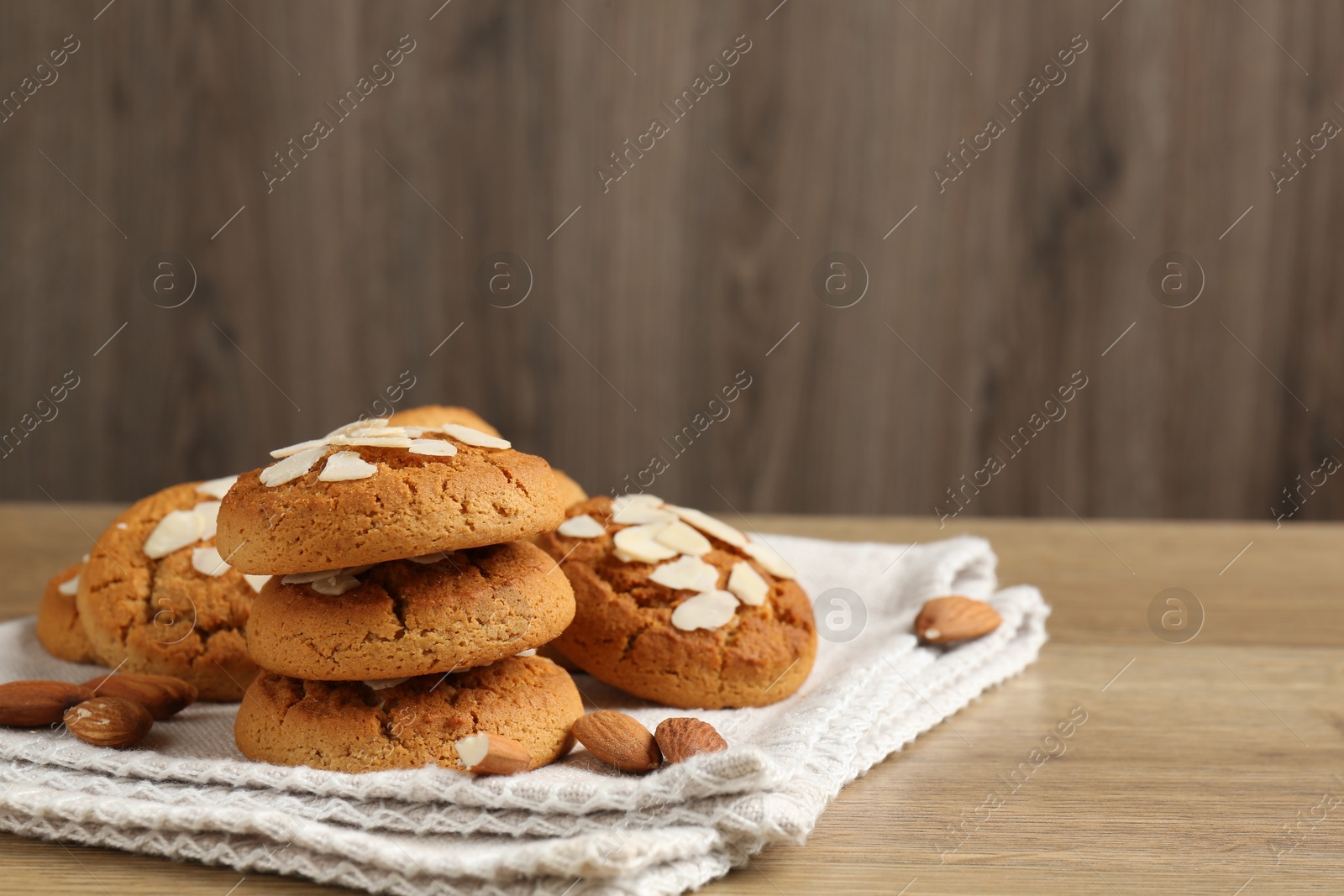 Photo of Tasty cookies with almond flakes and nuts on wooden table. Space for text