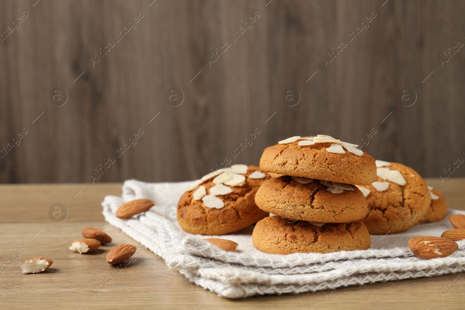 Photo of Tasty cookies with almond flakes and nuts on wooden table. Space for text