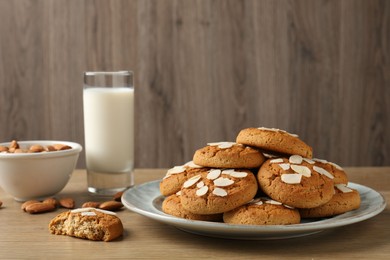 Photo of Tasty cookies with almond flakes, nuts and milk on wooden table