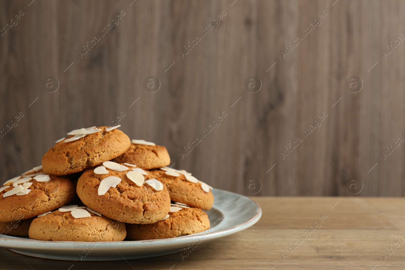 Photo of Tasty cookies with almond flakes on wooden table, closeup. Space for text