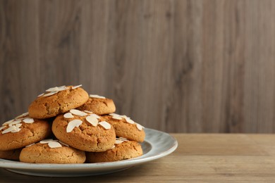 Photo of Tasty cookies with almond flakes on wooden table, closeup. Space for text