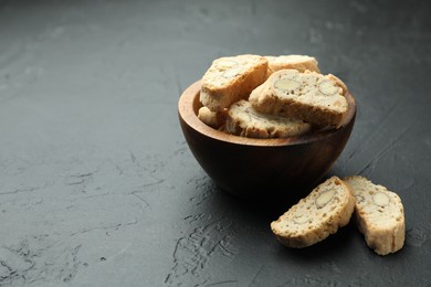 Photo of Traditional Italian almond biscuits (Cantucci) in bowl on black table, space for text