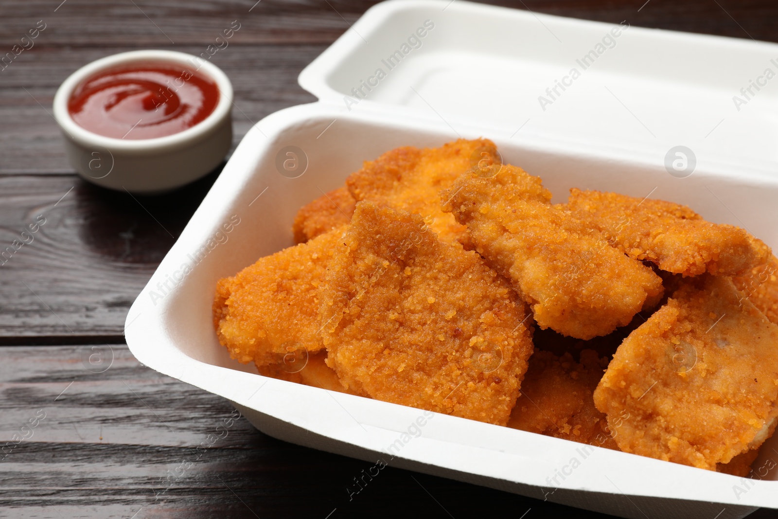 Photo of Tasty chicken nuggets and sauce on wooden table, closeup