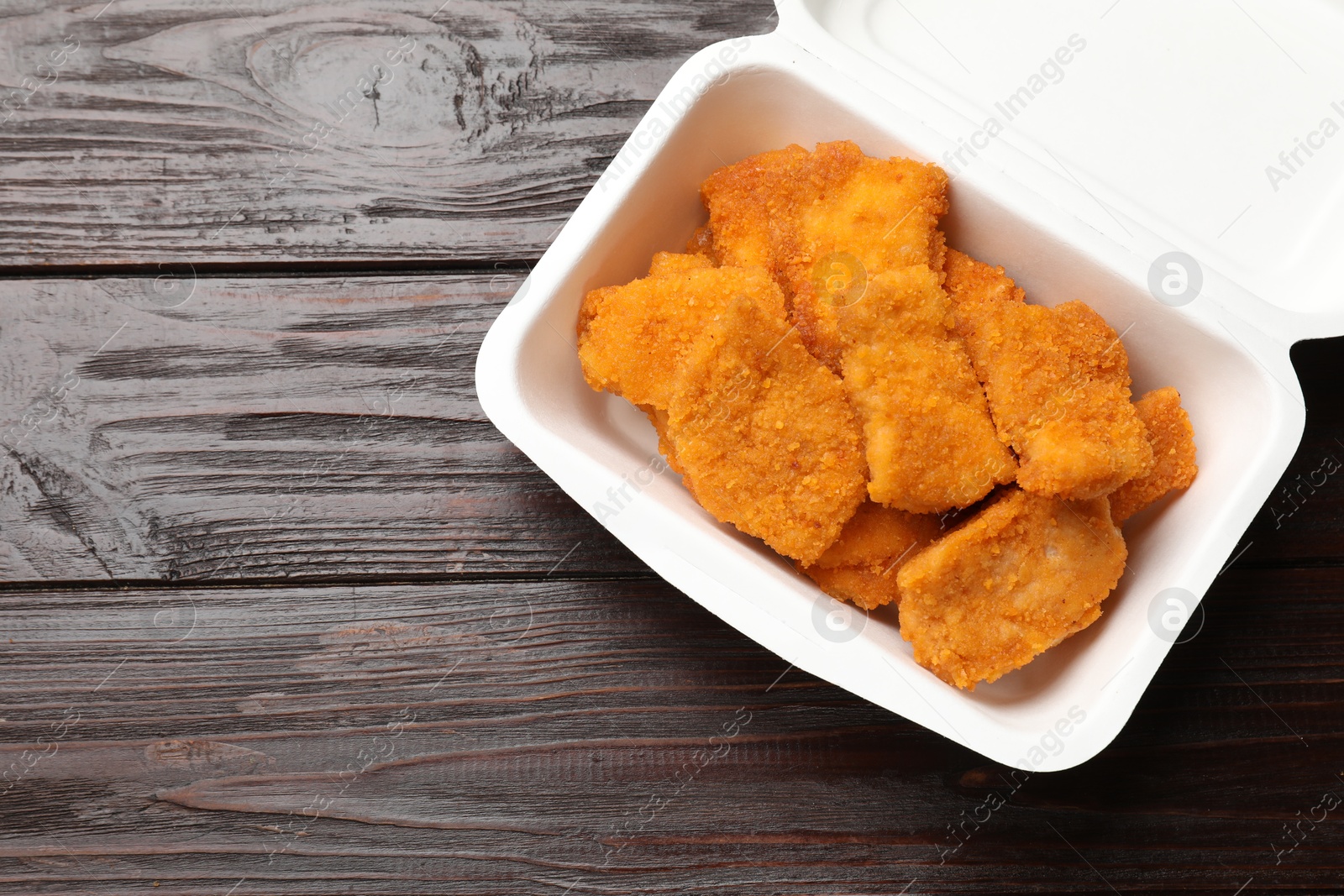 Photo of Tasty chicken nuggets on wooden table, top view. Space for text