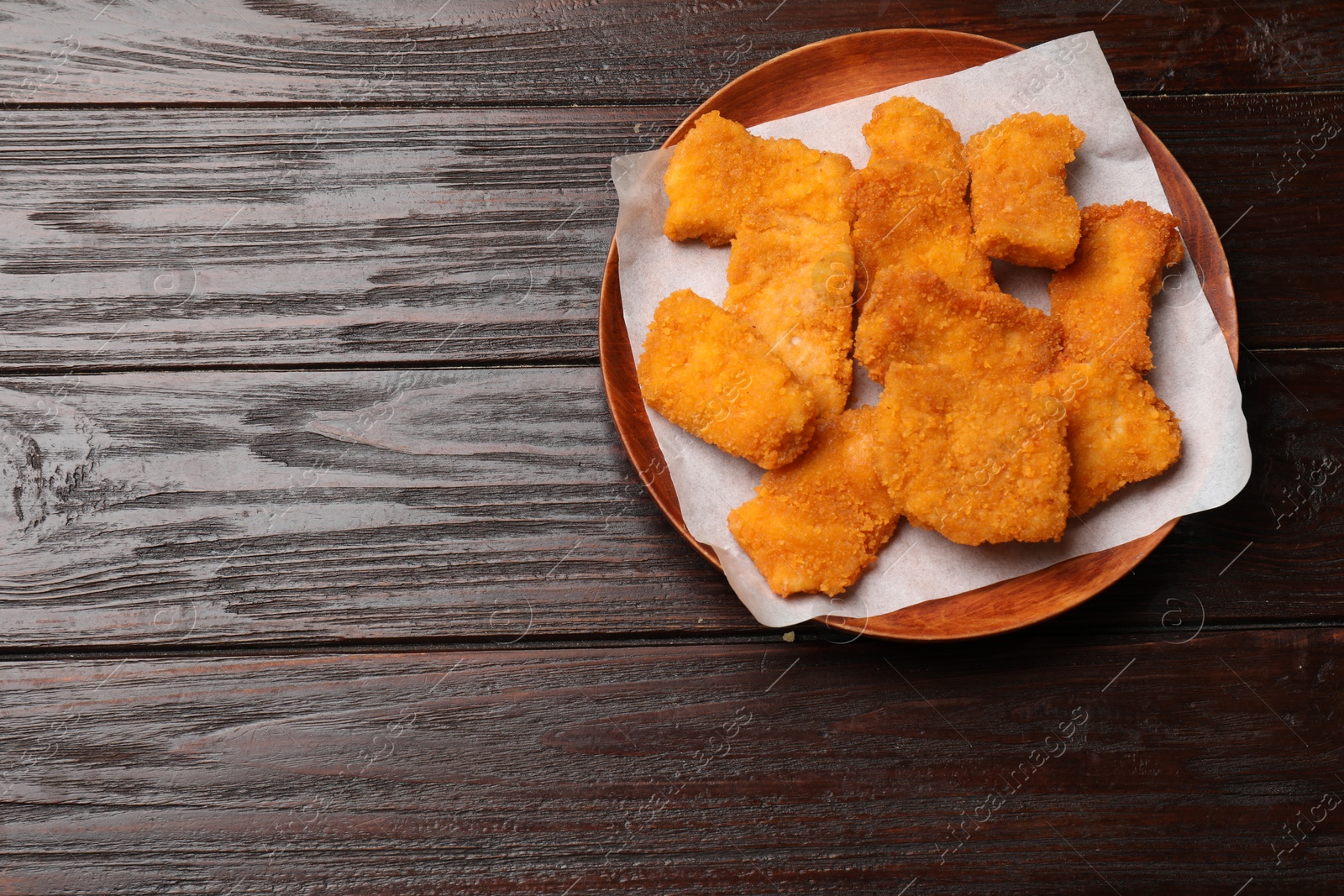 Photo of Tasty chicken nuggets on wooden table, top view. Space for text