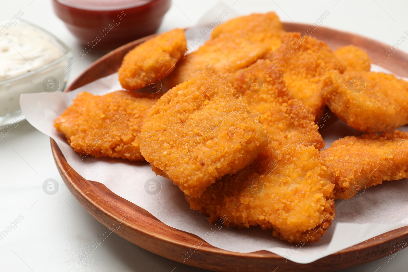 Photo of Tasty chicken nuggets on white table, closeup