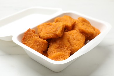 Photo of Tasty chicken nuggets on white marble table, closeup