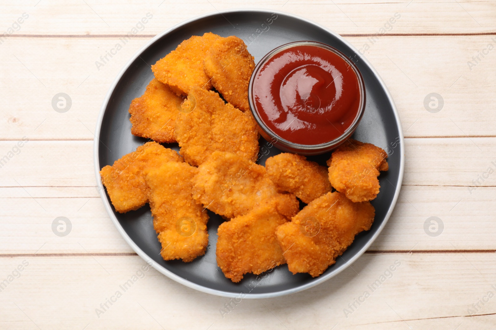 Photo of Tasty chicken nuggets and sauce on wooden table, top view