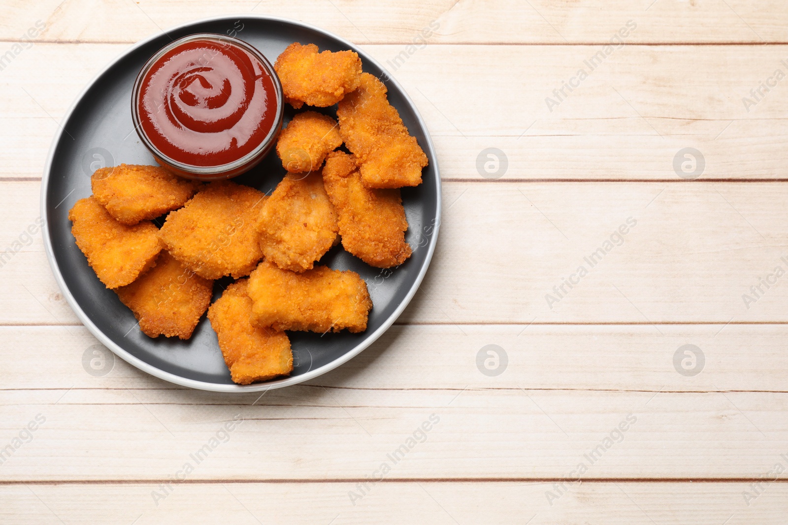 Photo of Tasty chicken nuggets and sauce on wooden table, top view. Space for text