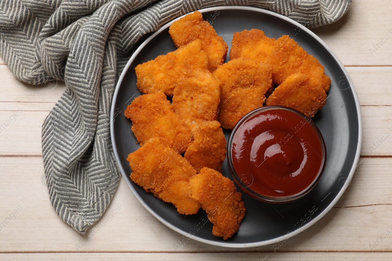 Photo of Tasty chicken nuggets and sauce on wooden table, top view