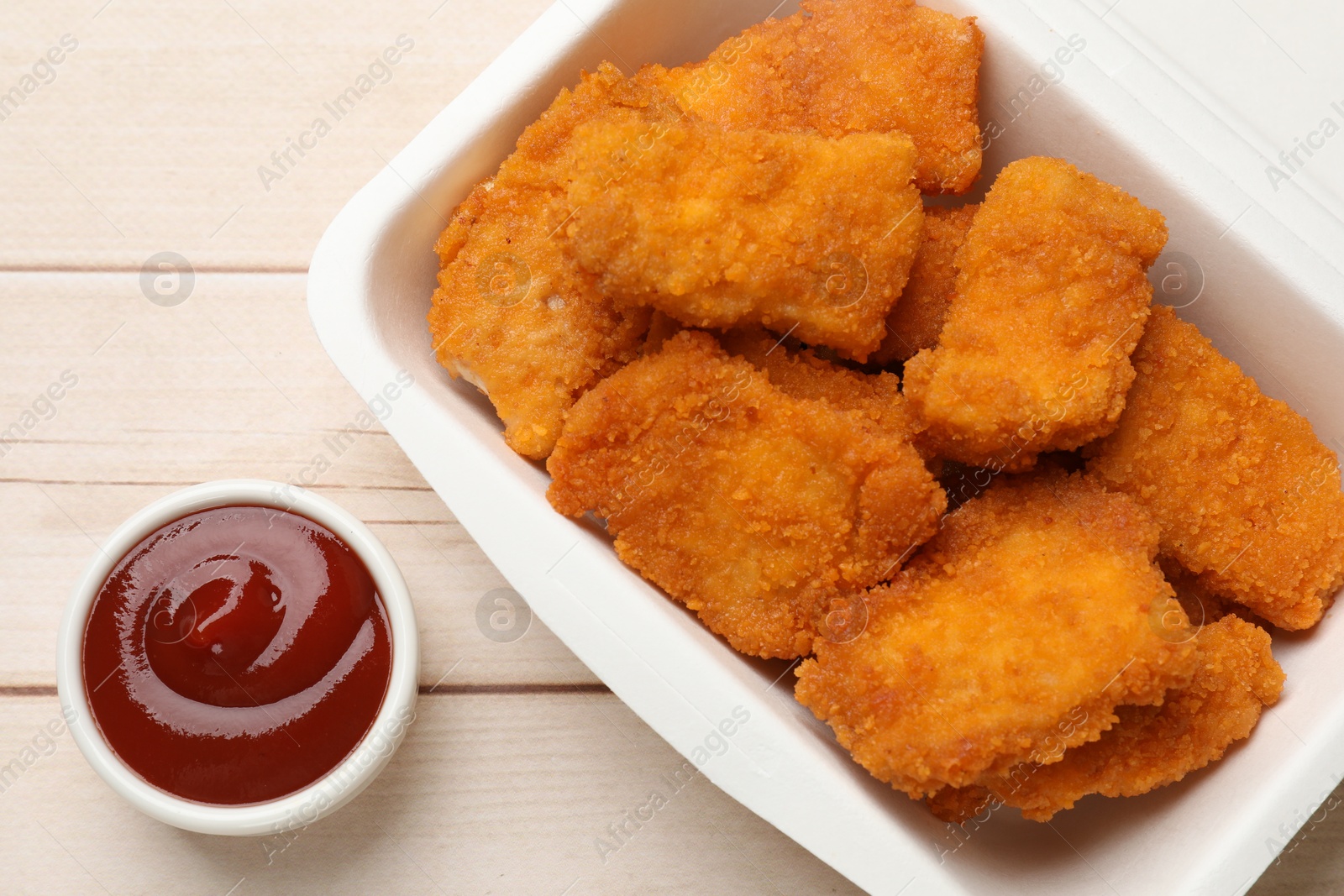 Photo of Tasty chicken nuggets and sauce on wooden table, top view