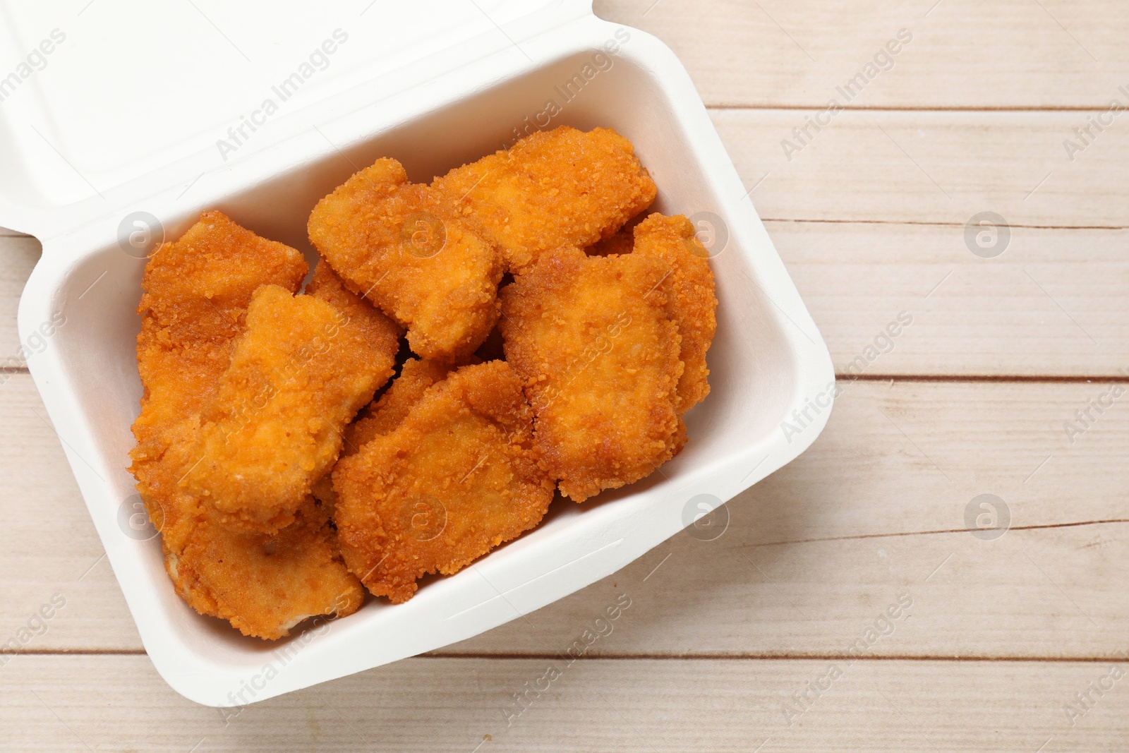 Photo of Tasty chicken nuggets on wooden table, top view. Space for text