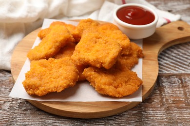 Photo of Delicious chicken nuggets with ketchup on wooden table, closeup