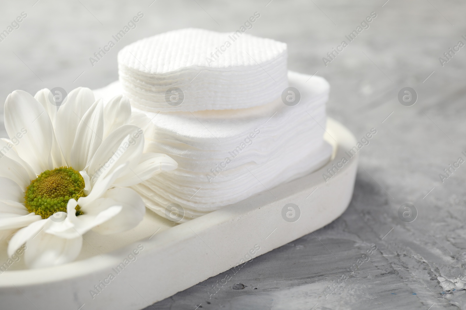 Photo of Clean cotton pads and flower on grey table, closeup