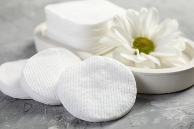 Photo of Clean cotton pads and flower on grey table, closeup