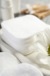 Photo of Clean cotton pads and flower on grey table, closeup