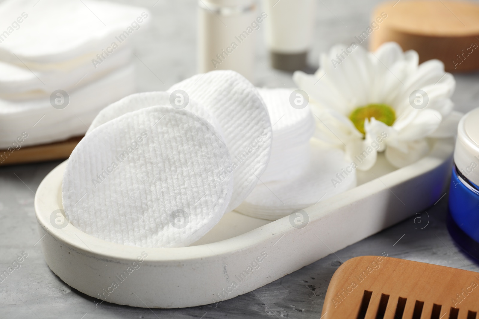 Photo of Clean cotton pads and flower on grey table, closeup