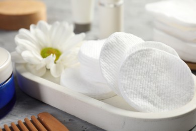 Photo of Clean cotton pads and flower on grey table, closeup