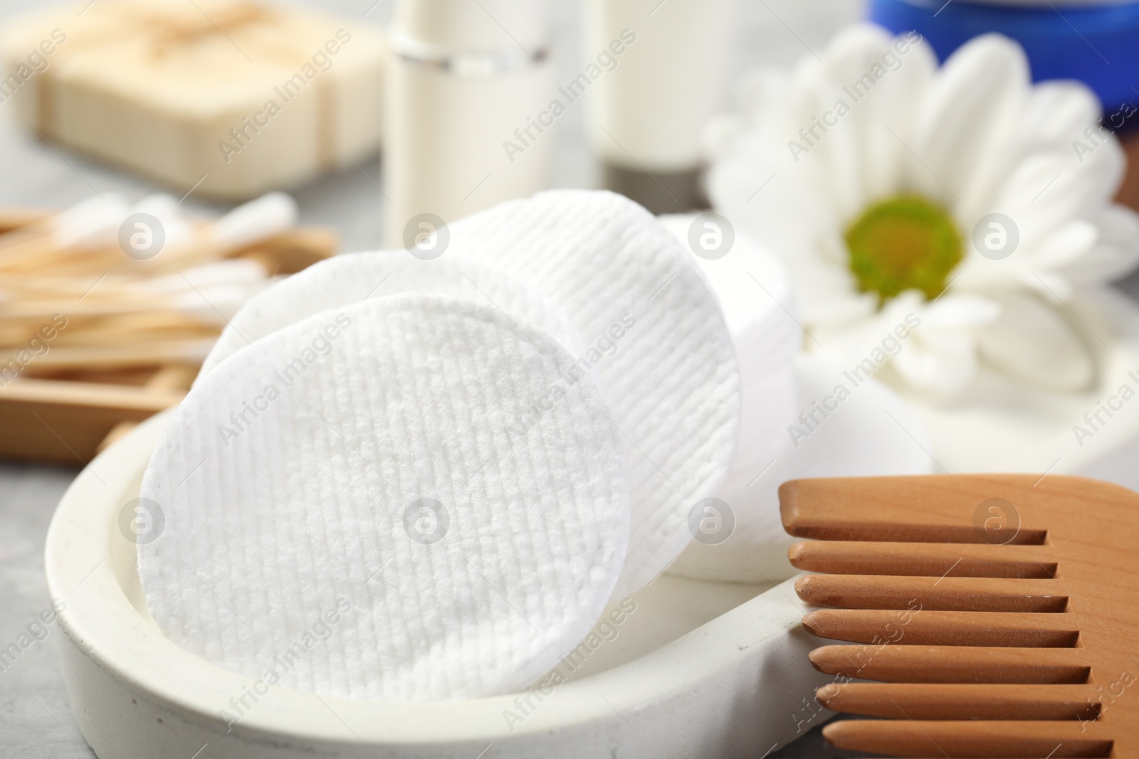 Photo of Clean cotton pads and comb on grey table, closeup