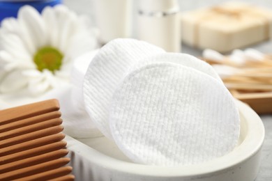 Photo of Clean cotton pads and comb on grey table, closeup