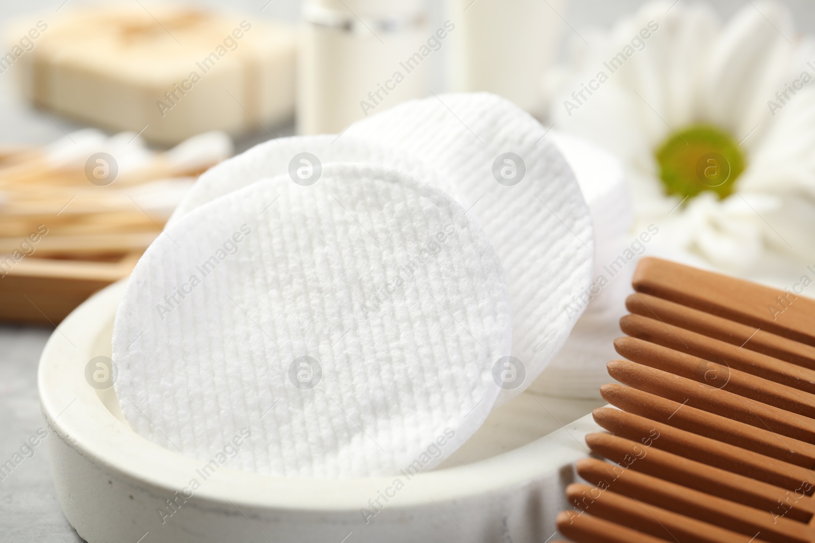 Photo of Clean cotton pads and comb on grey table, closeup