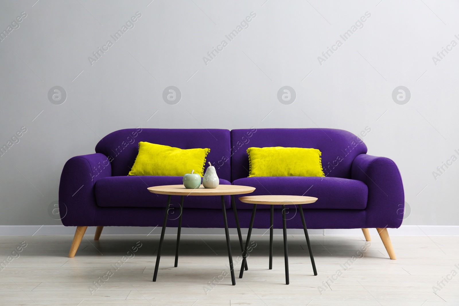 Image of Comfortable sofa and nesting tables near grey wall in room