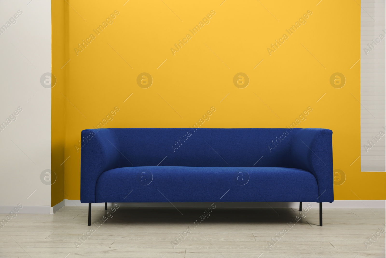 Image of Stylish blue sofa near golden wall indoors