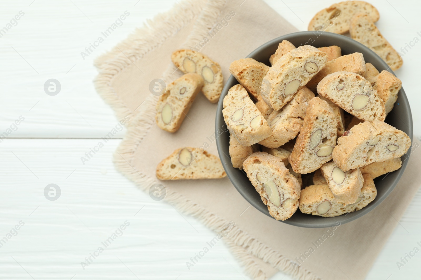 Photo of Traditional Italian almond biscuits (Cantucci) in bowl on white wooden table, top view