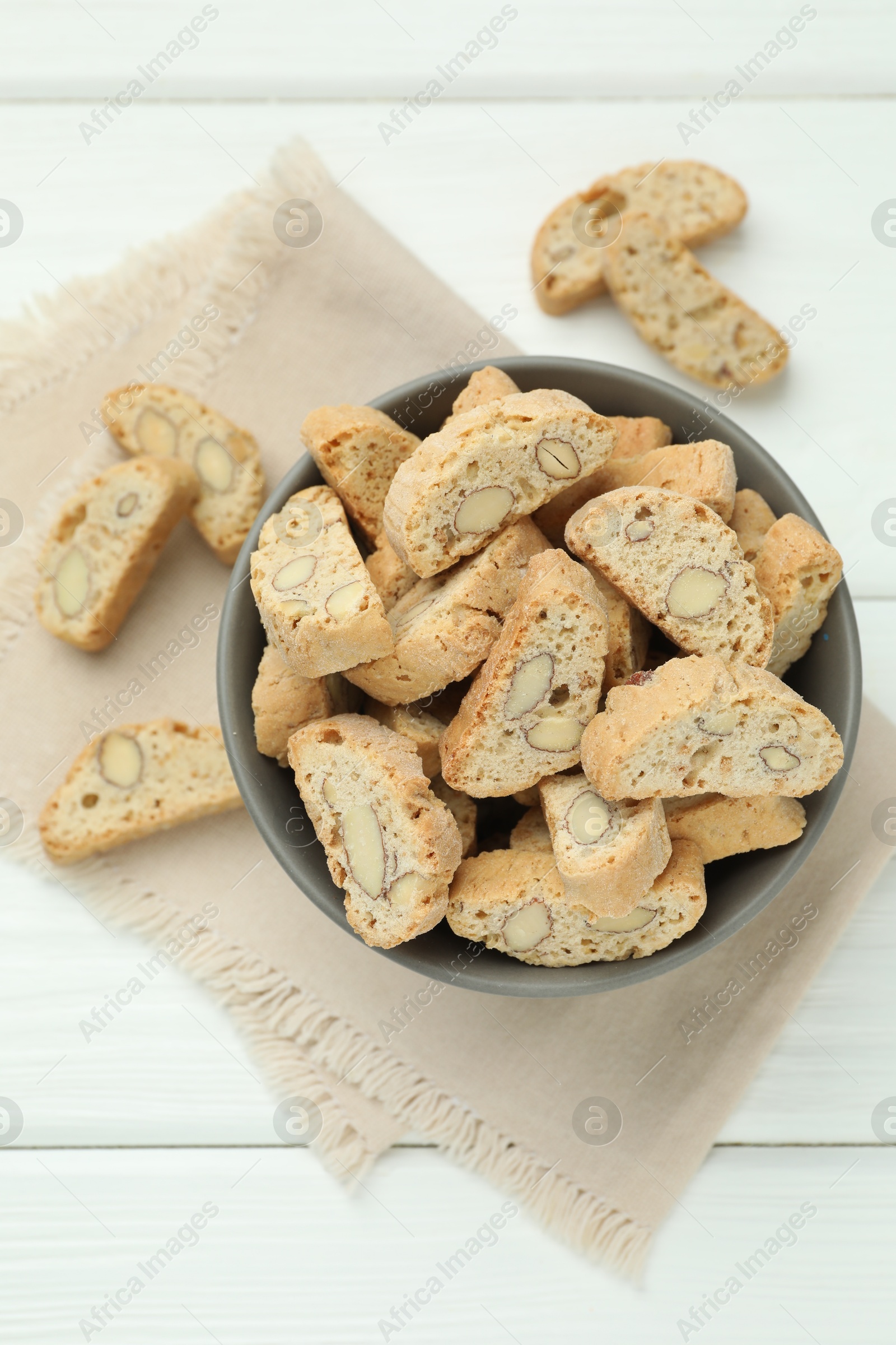 Photo of Traditional Italian almond biscuits (Cantucci) in bowl on white wooden table, top view