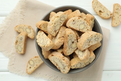 Photo of Traditional Italian almond biscuits (Cantucci) in bowl on white wooden table, top view