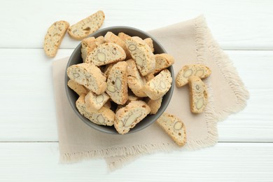 Photo of Traditional Italian almond biscuits (Cantucci) in bowl on white wooden table, top view