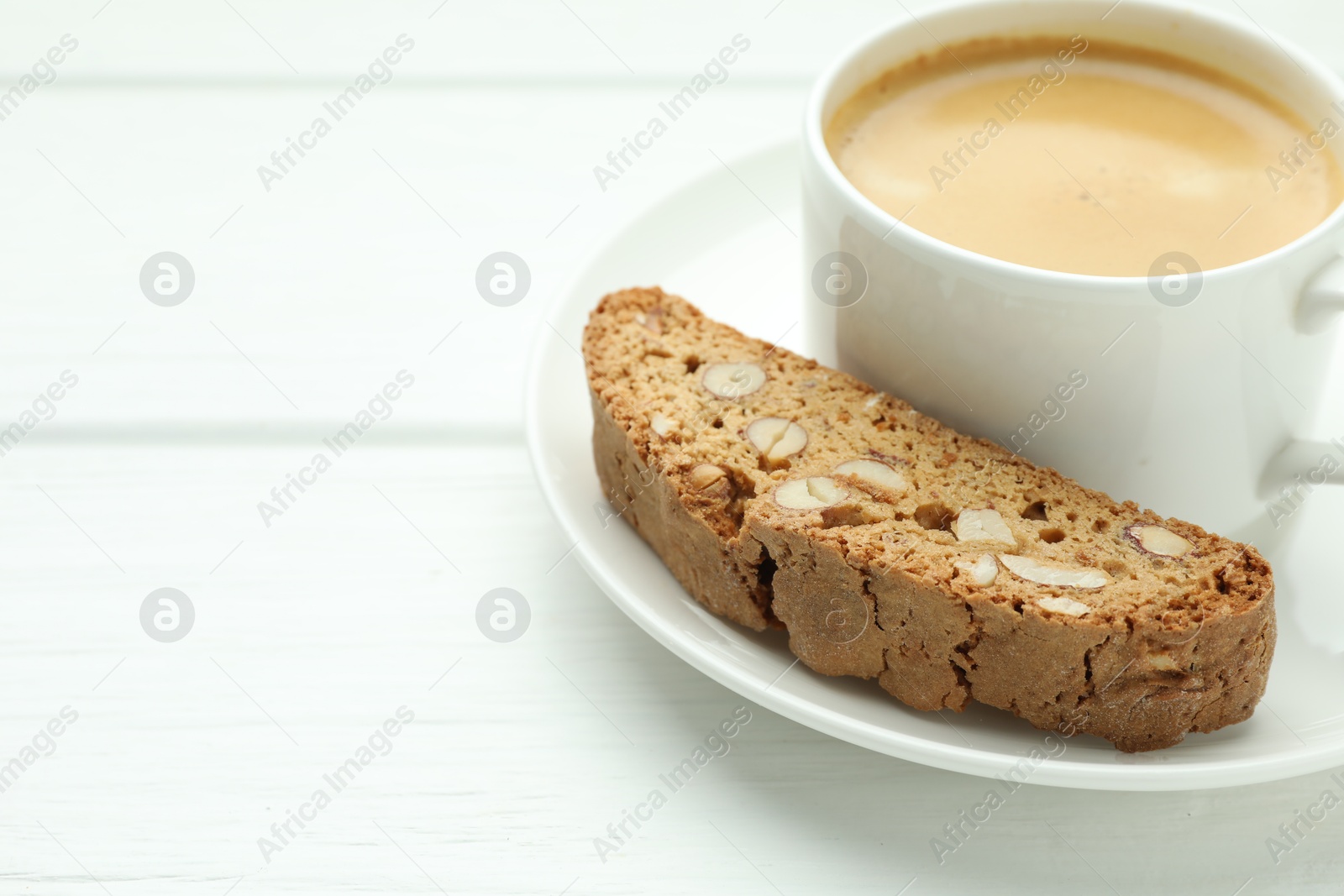 Photo of Traditional Italian almond biscuit (Cantucci) and coffee on white wooden table, closeup. Space for text