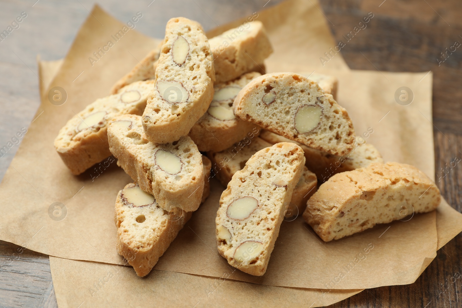 Photo of Traditional Italian almond biscuits (Cantucci) and nuts on wooden table, closeup