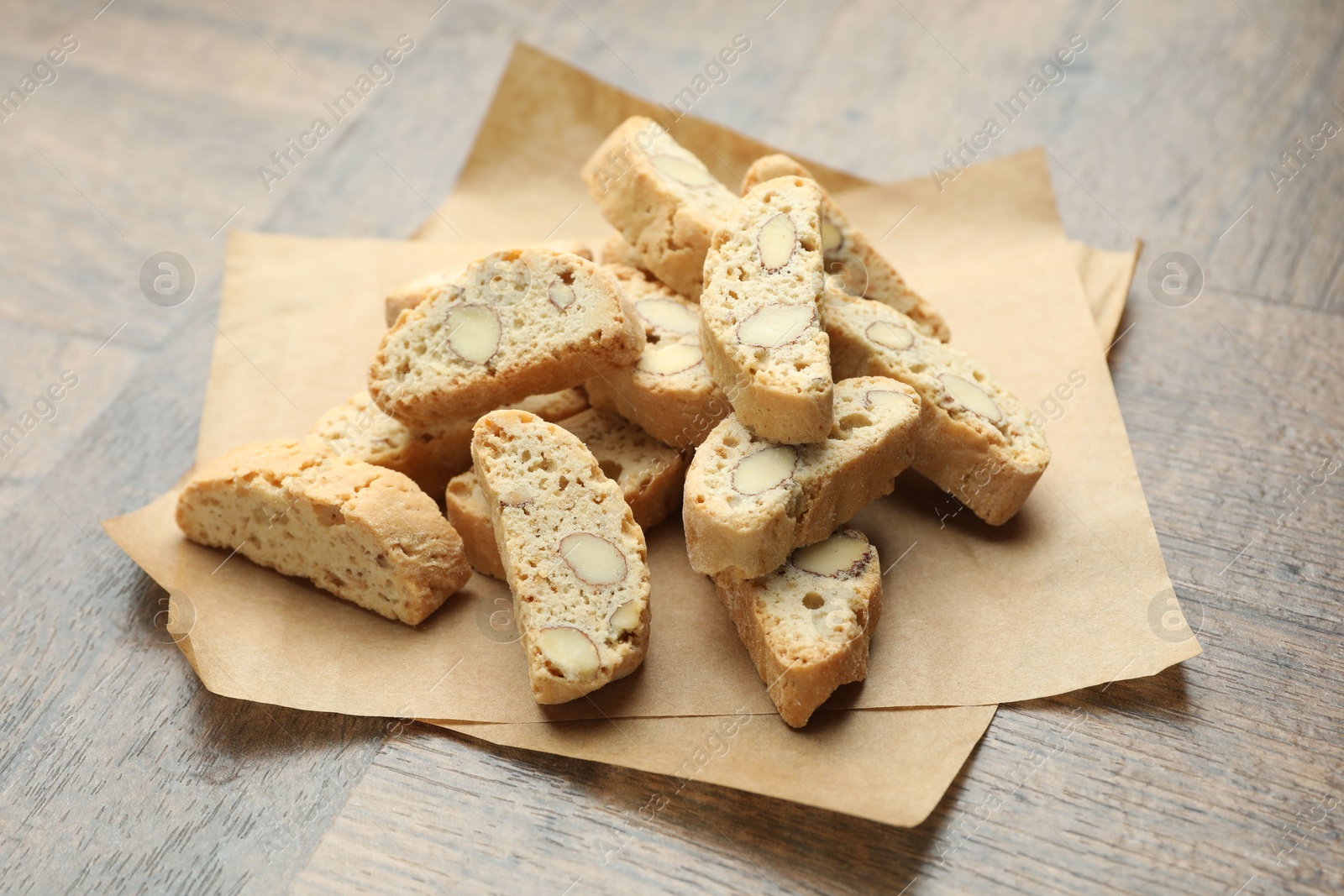 Photo of Traditional Italian almond biscuits (Cantucci) and nuts on wooden table, closeup