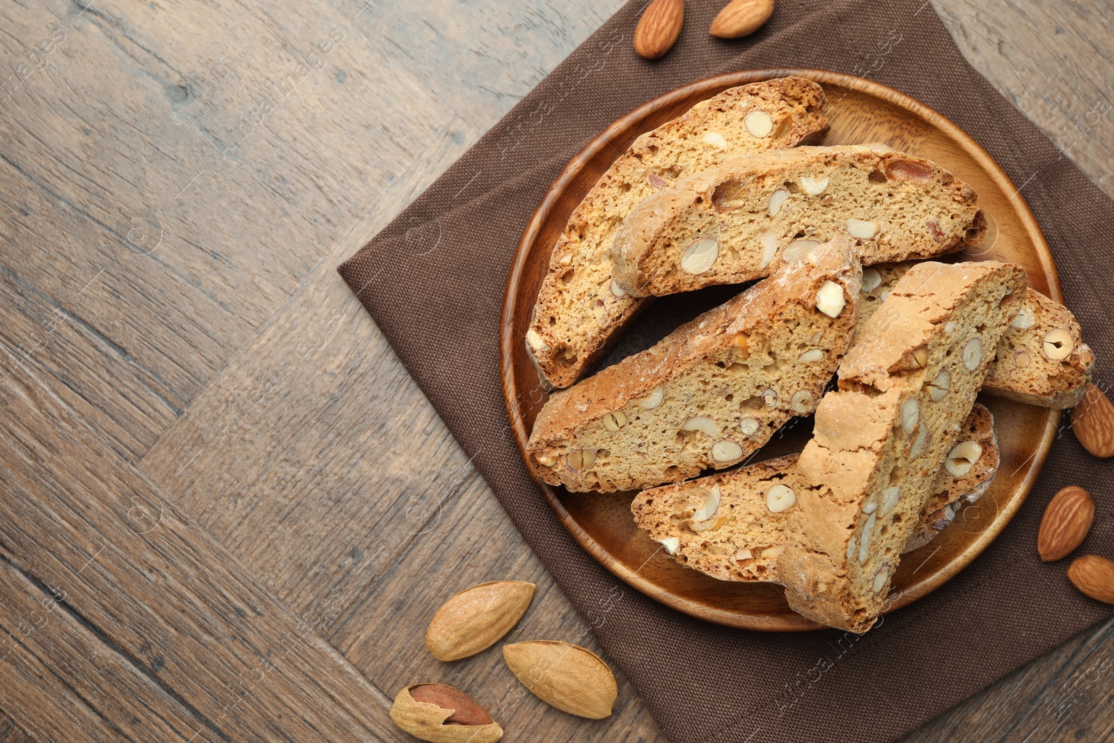 Photo of Traditional Italian almond biscuits (Cantucci) and nuts on wooden table, top view. Space for text