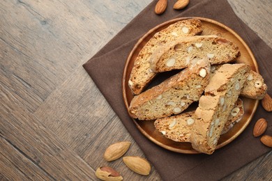 Photo of Traditional Italian almond biscuits (Cantucci) and nuts on wooden table, top view. Space for text